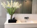 Modern bathroom interior with a sink, mirror, and decorative flowers