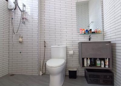 Modern white-tiled bathroom with shower and storage space