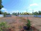 Spacious residential land with perimeter fencing and young palm trees