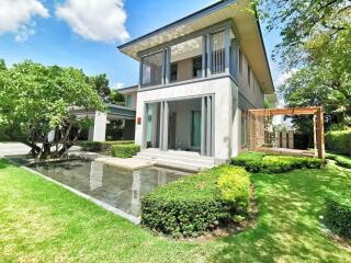 Modern two-story house with lush garden and pond