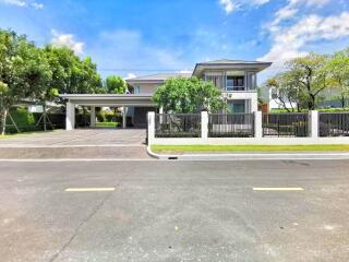 Modern two-story house with a spacious driveway and lush greenery under a clear blue sky