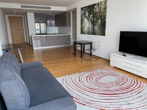 Spacious living room with open kitchen design, modern furniture, and large nature-themed wall art