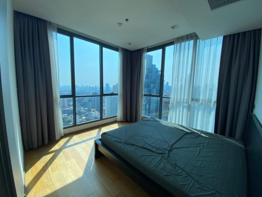 Modern bedroom with large windows and city skyline view