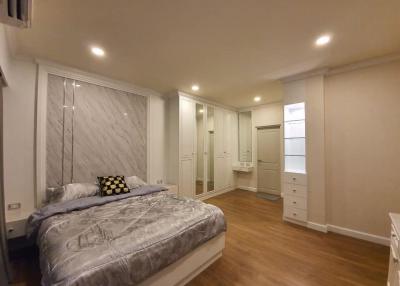 Spacious bedroom with modern design, well-lit with recessed ceiling lights, featuring a large bed and ample storage space