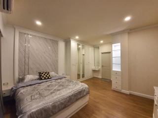 Spacious bedroom with modern design, well-lit with recessed ceiling lights, featuring a large bed and ample storage space