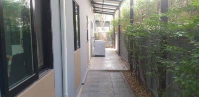 Narrow outdoor passageway with tiled floor and green plants