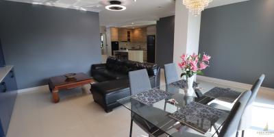 Spacious living room with modern furniture and open plan kitchen in the background