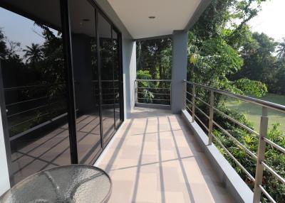 Spacious balcony with a view of greenery and seating area