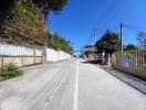 A sunny residential street with fences and lush greenery