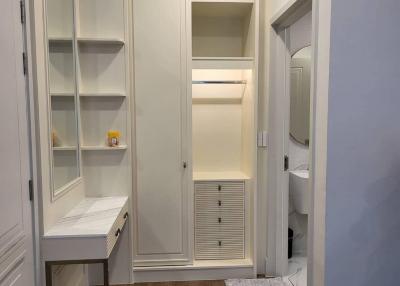 Modern hallway with built-in storage cabinets and wooden flooring leading to bathroom