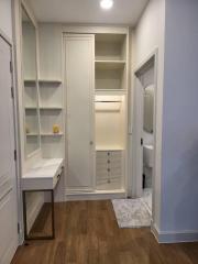 Modern hallway with built-in storage cabinets and wooden flooring leading to bathroom
