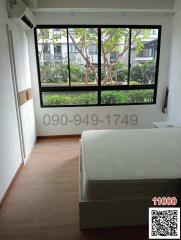 Bright bedroom with large window view of greenery