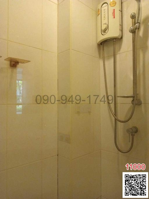 Bathroom with wall-mounted electric shower and white tile finish