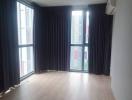 Spacious unfurnished living room with large windows and hardwood flooring
