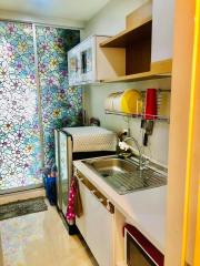 Compact and colorful kitchen with modern appliances and floral wallpaper