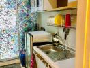 Compact and colorful kitchen with modern appliances and floral wallpaper