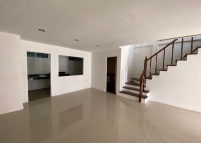 Spacious and well-lit living room with staircase and access to kitchen