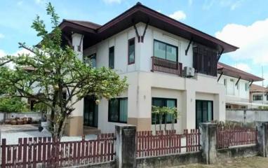 Two-story residential house with a balcony and a tree in the front yard