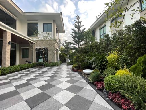 Elegant residential exterior with checkered pathway and green landscaping