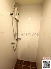 Compact bathroom shower area with white tiles and electric shower unit
