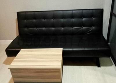 Modern living room with black leather sofa and a small wooden coffee table