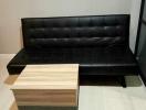 Modern living room with black leather sofa and a small wooden coffee table