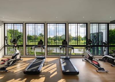 Spacious home gym with large windows overlooking a serene outdoor view