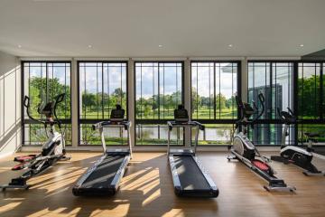 Spacious home gym with large windows overlooking a serene outdoor view