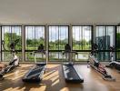 Spacious home gym with large windows overlooking a serene outdoor view