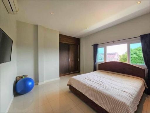Spacious bedroom with king-sized bed, wooden wardrobe, and exercise ball near window