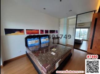 Modern bedroom with unmade bed, art on the wall, and city view through glass door