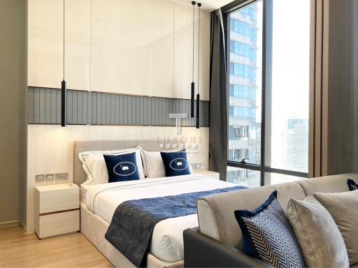 Modern bedroom with large bed, city view, and comfortable furnishings