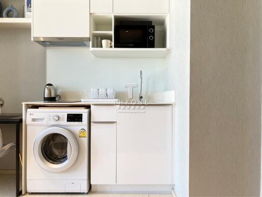 Compact modern kitchen with white cabinets, built-in appliances, and washing machine