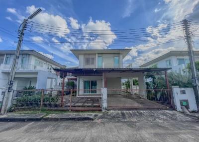 Two-story residential house with a front yard and cloudy sky