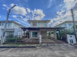 Two-story residential house with a front yard and cloudy sky