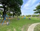 Community playground with green lawn and trees