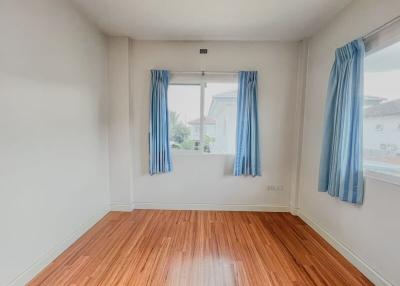 Bright empty bedroom with hardwood floors and blue curtains