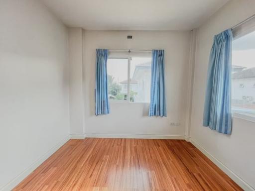 Bright empty bedroom with hardwood floors and blue curtains