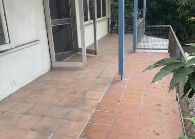 Spacious outdoor patio area with tile flooring and garden view
