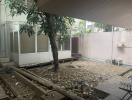 Backyard area with a tree and construction debris