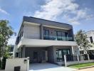 Modern two-story house with a spacious driveway under a clear blue sky