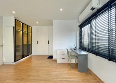 Bright contemporary bedroom with wooden flooring, fitted wardrobes, and a workspace