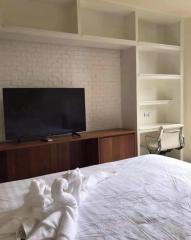 Cozy bedroom with white brick accent wall and built-in shelving