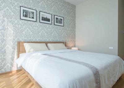 Modern bedroom with patterned wallpaper and framed photographs