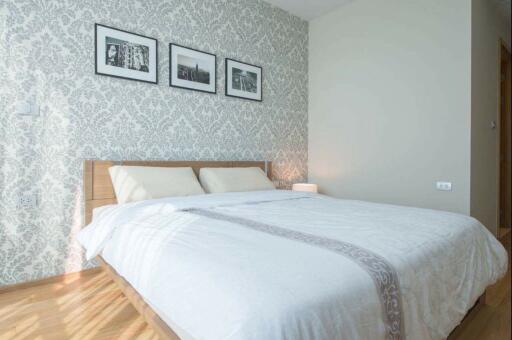 Modern bedroom with patterned wallpaper and framed photographs