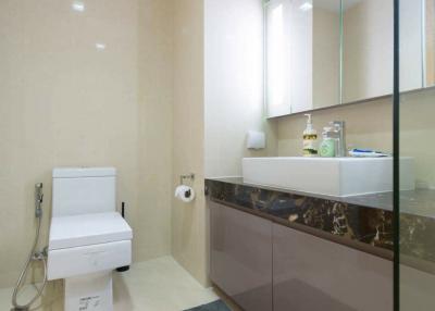 Modern bathroom with beige tiles, glass shower partition, and floating vanity