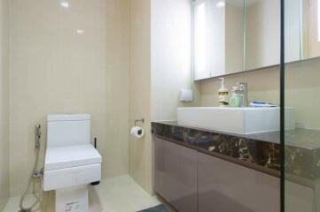 Modern bathroom with beige tiles, glass shower partition, and floating vanity