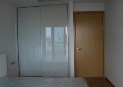 Spacious bedroom with large mirrored wardrobe and natural wood door