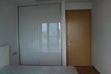 Spacious bedroom with large mirrored wardrobe and natural wood door