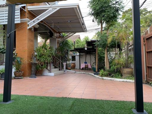 Spacious backyard patio with artificial grass and shaded seating area